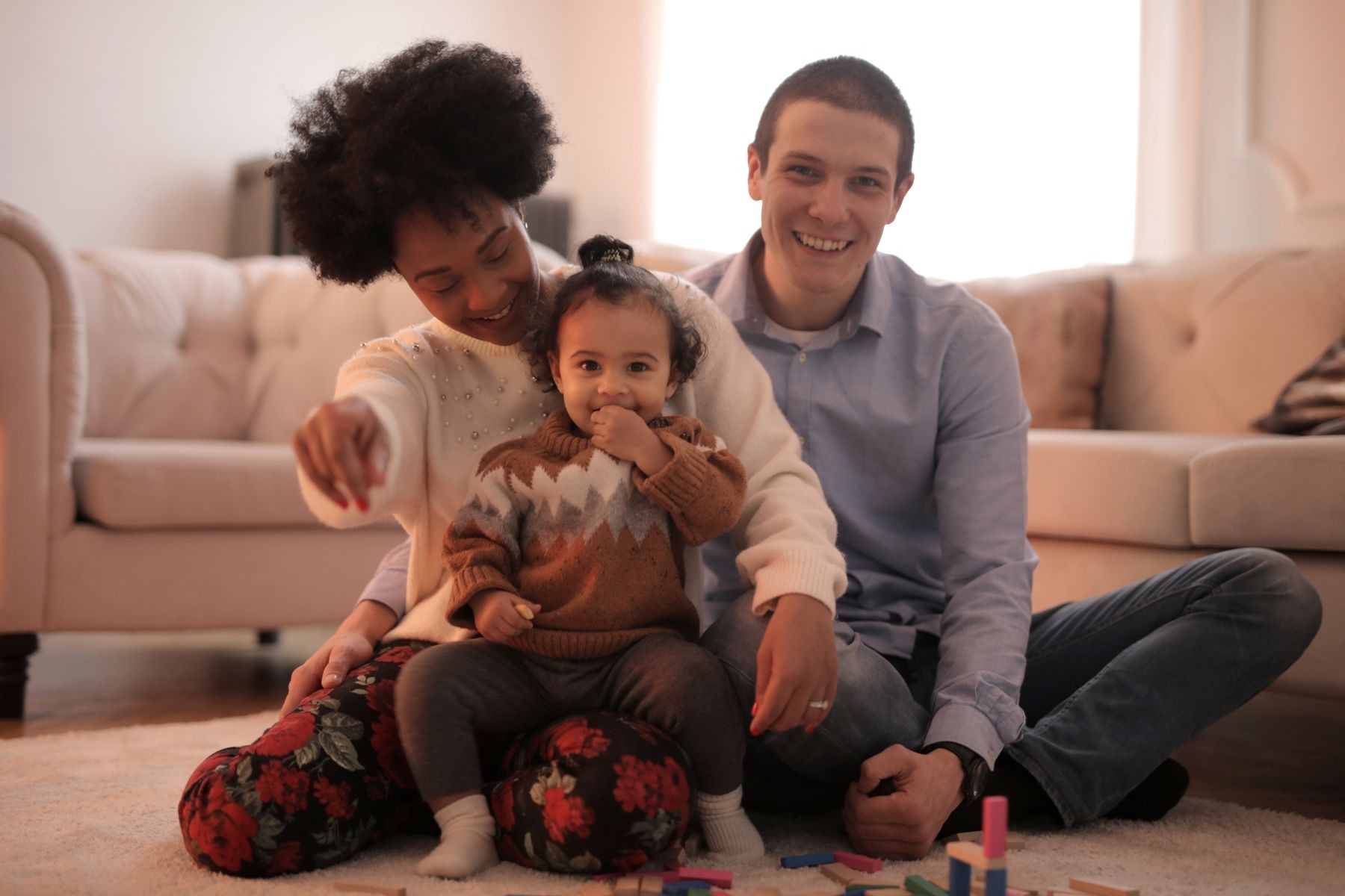 A family sitting together on the floor of their living room.
